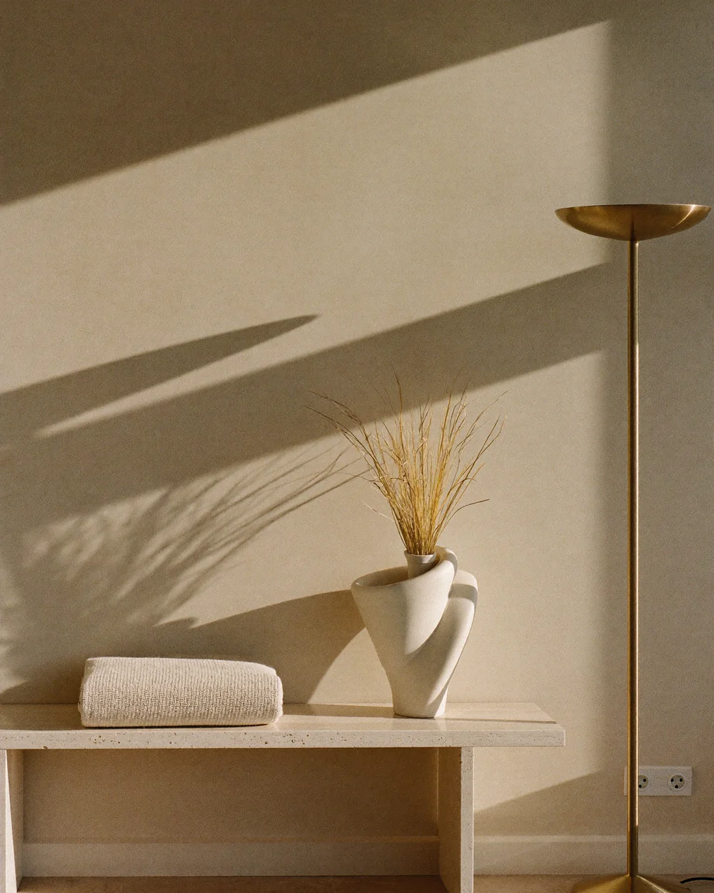 Recepção de clínica com luz natural, banco de travertino e vaso